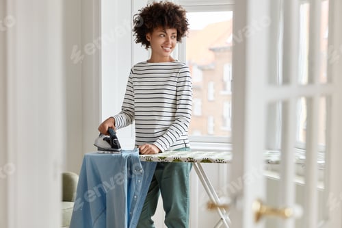 Vista previa: Everyday Routine And Household Concept. Positive Young Dark Skinned Wife With Afro Hairstyle, Irons