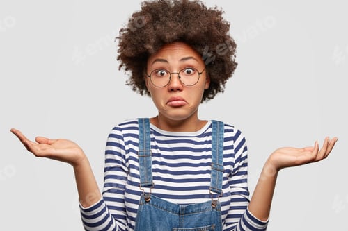 Preview: Clueless African American Female With Curly Bushy Hair, Shrugs Shoulders, Looks Doubtfully As Faces