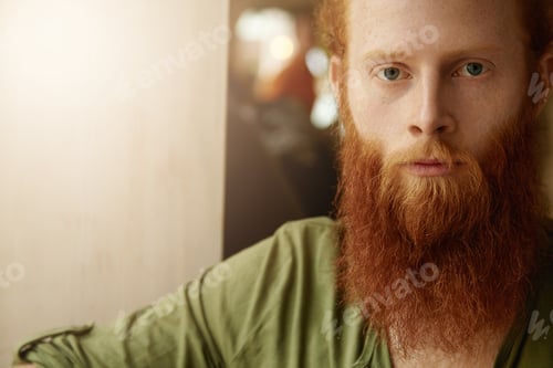 Preview: Portrait Of Young Redhead Man With Stylish Beard Dressed Casually, Sitting At Cafeteria Alone