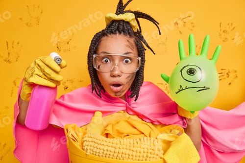 Preview: Surprised Dark Skinned Female Housekeeper Stares At Camera Holds Detergent And Inflated Balloon