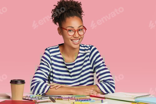 Preview: Happy Ethnic Student Designer Draws Sketch For University Exam, Wears Striped Jacket And Glasses