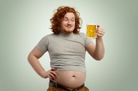 Vorschau: Glücklicher rothaariger übergewichtiger Mann mit dickem Bauch, der aus seinem geschrumpften T-Shirt herausragt und ein Glas hält