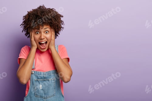 Preview: Impressed Emotional Woman Looks With Terror, Shouts And Keeps Mouth Widely Opened, Touches Faces