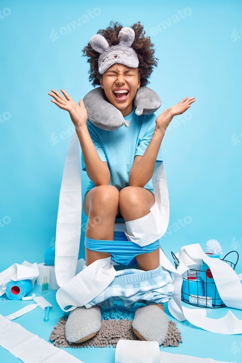 Preview: Emotional Young Woman Raises Hands And Exclaims Loudly Dressed In Pajama Sleepmask Sits On Toilet