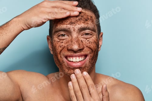 Preview: Photo Of Cheerful Caucasian Man With Coffee Scrub Mask On Face, Touches Forehead And Chin, Smiles