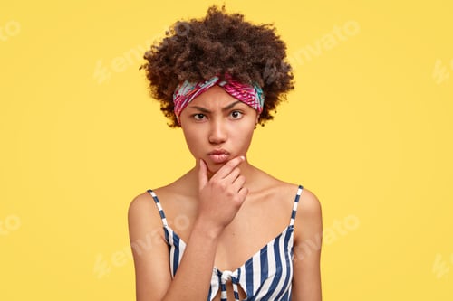 Preview: Displeased Angry Dark Skinned Young Woman Holds Chin, Claims About Something Bad, Has Sullen