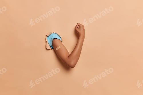 Preview: Thin Nice Female Hand In Blue Tshirt Breaks Through The Paper Wall, Shows Muscles And Compressed