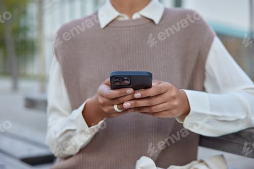 Preview: Cropped Shot Of Unknown Woman In Elegant Clothes Holds Mobile Phone Surfs Wireless Internet Makes
