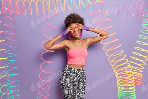 Preview: Upbeat Cheerful Dark Skinned Young Woman Covers Eyes And Smiles Broadly, Has Fun Indoor, Dressed In