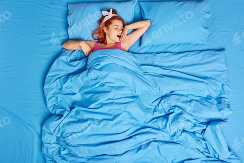 Preview: Young Tired Redhead Woman Stretches Arms And Yawns Wants To Sleep Wears Headband Lying In