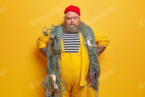 Preview: Serious Fisherman Looks With Confident Expression, Keeps Hands On Hips, Wears Striped Sailor Shirt