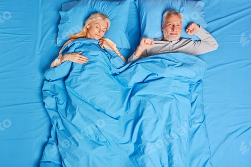 Preview: Glad Bearded Mature Man Stretches In Bed Feels Pleasure After Healthy Sleep. Beautiful Middle Aged