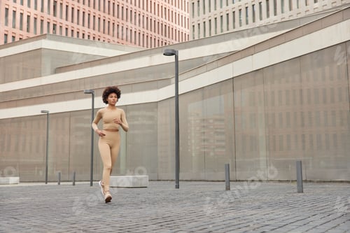 Preview: Young Active Curly Haired Woman Runs In City Dressed In Sportswear And Comfortable Sneakers Shows