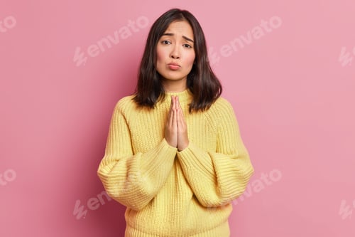 Preview: Hopeless Brunette Woman Keeps Palms Pressed Together And Looks With Imploring Expression Begs For