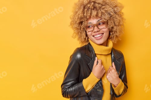 Preview: Indoor Shot Of Happy Joyful Woman With Curly Hair Looks Gladfully At Something Being In Good Mood