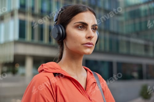 Preview: Outdoor Shot Of Serious Brunette Young Woman Leads Sporty Lifestyle Listens Music Via Headphones
