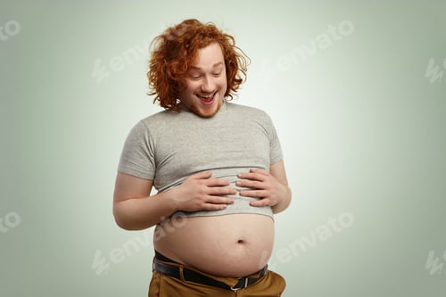Preview: Indoor Shot Of Funny Overweight Young Caucasian Male Wearing Undersized Grey T-Shirt, Holding Hands