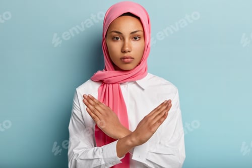Preview: Indoor Shot Of Serious Muslim Woman Makes Denial Hand Gesture, Keeps Arms Crossed Over Chest