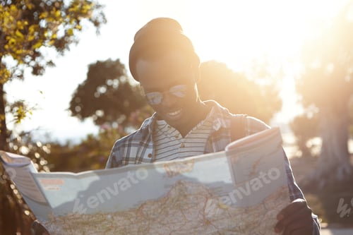 Preview: Charismatic Black Hipster In Sun Rays Lost In Forest, Holding City Guide, Looking Happy And Super