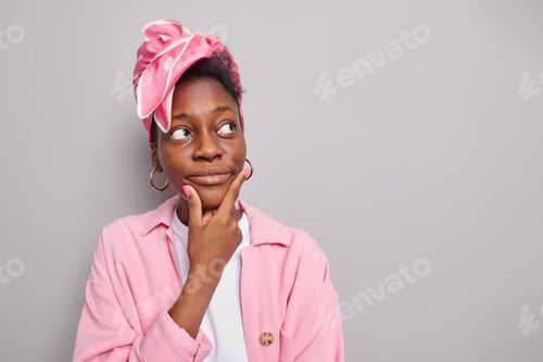 Preview: Portrait Of Serious Dark Skinned Woman Holds Chin Looks Away With Pensive Expression Considers