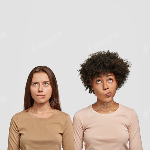 Preview: Vertical Shot Of Two Confused Multiethnic Women Bite Lower Lips, Looks With Puzzlement Upwards