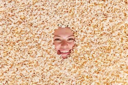 Preview: Cheerful Womans Face Covered With Tasty Delicious Popcorn With Important Nutrients And Variety Of