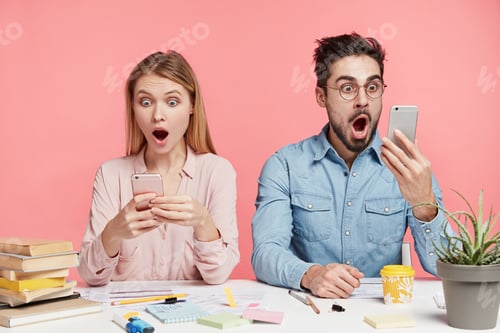 Preview: Portrait Of Shocked Terrified Male And Female Stare At Mobile Phones, Type Messages Or Read