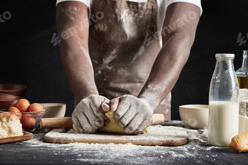 Preview: Unrecognizable Dark Skinned Male Baker Kneads Dough, Wears Apron Dirty In Flour, Surrounded With