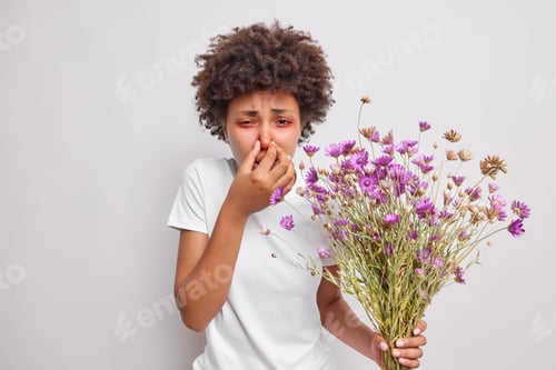 Preview: Curly Haired Sick Young Woman Covers Nose Suffers From Allergy Symptoms Holds Bouquet Of