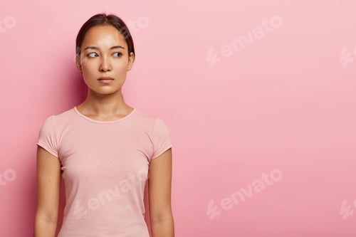 Preview: Half Length Shot Of Lovely Serious Woman Looks Aside On Blank Space, Has Pensive Expression