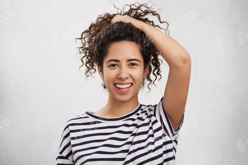 Preview: Adorable Teenage Girl With Curly Crisp Hair, Wears Striped Shirt, Makes Pony Tail, Advertises Nice