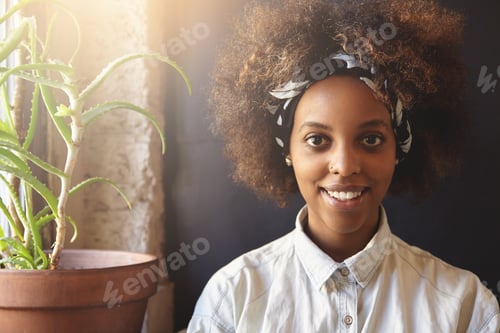 Preview: Fashionable Dark-Skinned Hipster Girl With Afro Haircut Wearing Denim Shirt And Do-Rag, Looking And