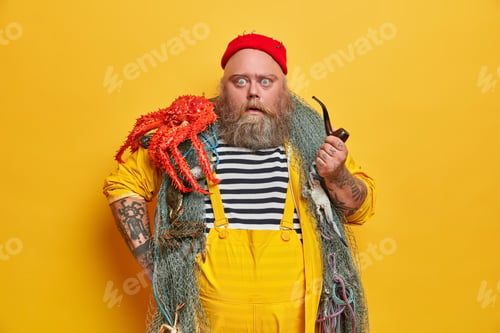 Preview: Skilled Male Mariner Has Stupefied Expression, Stares At Camera And Smokes Pipe. Fat Bearded