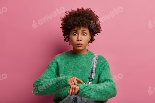 Preview: Look At Time. Worried Dark Skinned Curly Female Model Points At Wrist, Puzzled With Deadline, Being