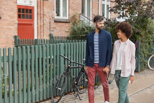 Preview: View Of Romantic Interracial Couple Hold Hands, Walk In Rural Setting, Look Positively At Each