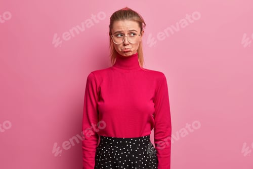 Preview: Young Dissatisfied European Woman Purses Lips And Has Unhappy Expression Looks Away Stands Offended