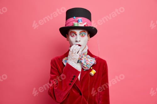 Preview: Mad Puzzled Male Hatter With Big Hat Has Fearful Expression And Bright Professional Makeup Poses