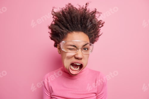Preview: Photo Of Crazy Mad Dark Skinned Ethnic Woman Winks Eye Keeps Mouth Opened Has Curly Hair Raised Up