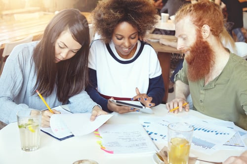 Preview: Multiracial Group Of Students Sitting At Table At University Canteen, Doing Their Home Assignment