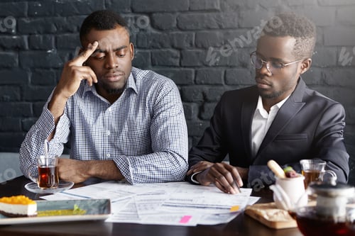Preview: Two African-American Businessmen Signing Contract During Business Meeting At Office Desk: Serious