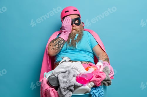 Preview: Plump Bearded Husband In Superhero Costume Helps Wife With Work About House Holds Basin Full Of