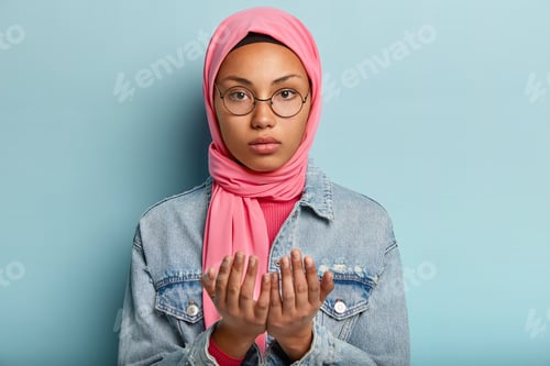 Preview: Serious Young Dark Skinned Woman Looks At Camera, Prays Indoor, Keeps Two Hands In Praying Gesture