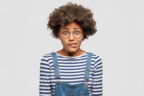 Preview: Embarrassed Beautiful African American Female Bites Lower Lip Nervously, Raises Eyebrows And Has