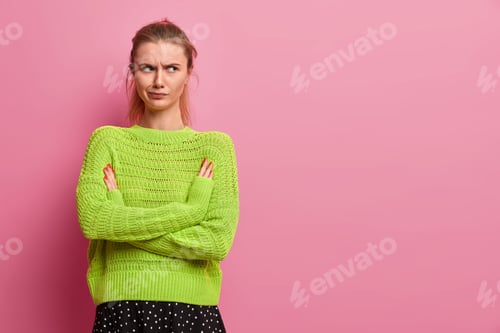 Preview: Displeased Young European Woman Being Angry With Boyfriend, Keeps Arms Folded, Smirks Face, Stands