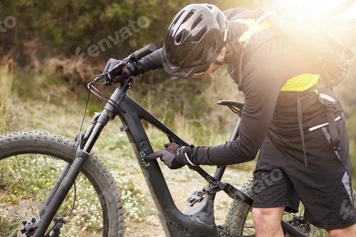 Preview: Unrecognizable Caucasian Biker In Helmet And Gloves Pressing Buttons On Frame Of His Black Electric