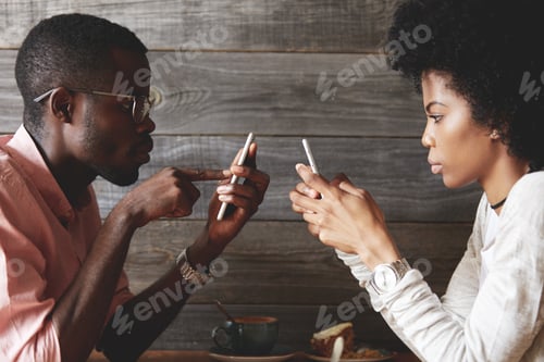 Preview: African American Young Students Sitting At A Cafe Table Using Mobile Phones, Texting Via Social