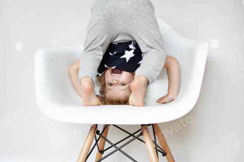 Preview: Indoor Portrait Of Beautiful Toddler Dressed In Stylish Pajamas With Stars, Trying To Do Somersault
