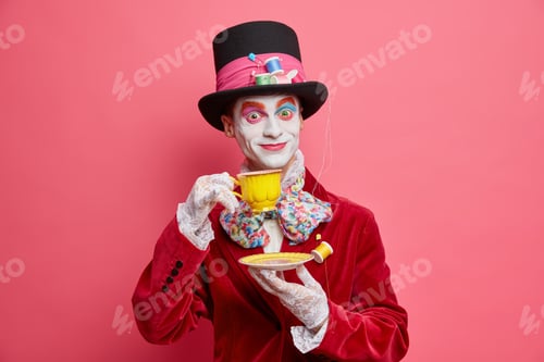 Preview: Crazy Hatter With Professional Vivid Colorful Halloween Makeup Dressed In Costume Poses With Cup Of