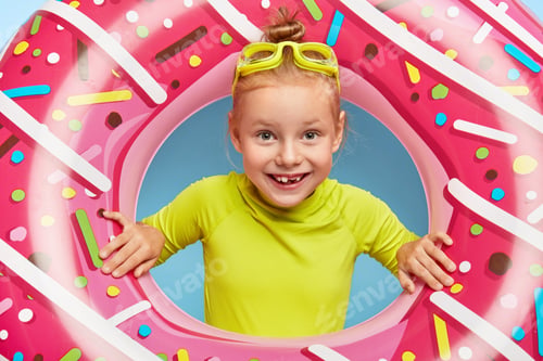 Preview: Close Up Portrait Of Cheerful Adorable Ginger Girl Sticks Head Through Pink Rubber Ring, Wears
