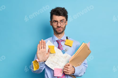 Preview: Serious Beatded Male Employee Says Hold On Pulls Palm Towards Camera In Stop Gesture Looks With